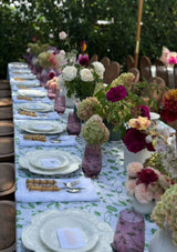 Elegant outdoor table setting with floral arrangements and white tablecloth.