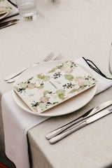 Table setting with linen napkins and tablecloth, floral menu card on a white plate