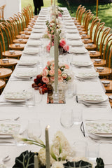 Long table set for a formal event with floral centerpieces and white tablecloth.