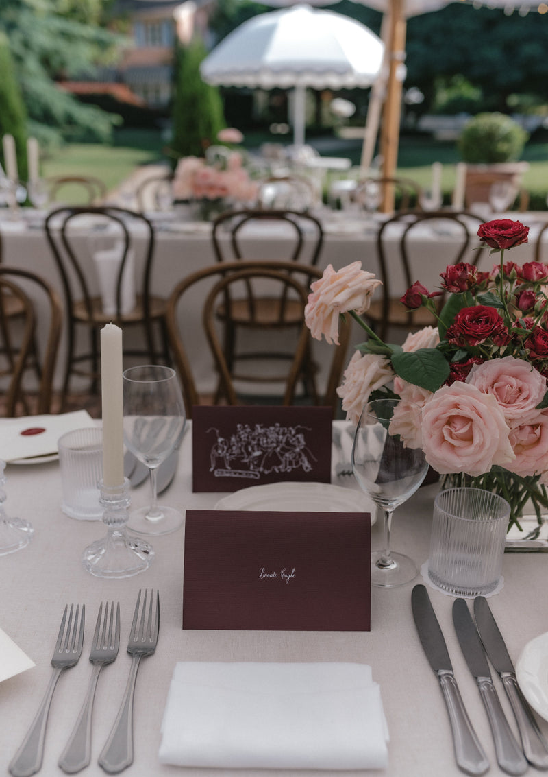 Elegant wedding reception setup with  linen tablecloth and napkins, floral arrangements, candles, and place cards.
